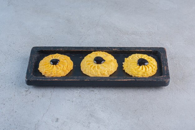 Foto gratuita un piatto nero di deliziosi biscotti rotondi su sfondo di pietra.