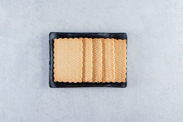 Black plate of tasty biscuits placed on stone.