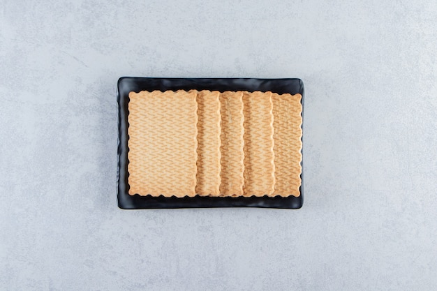 Black plate of tasty biscuits placed on stone.