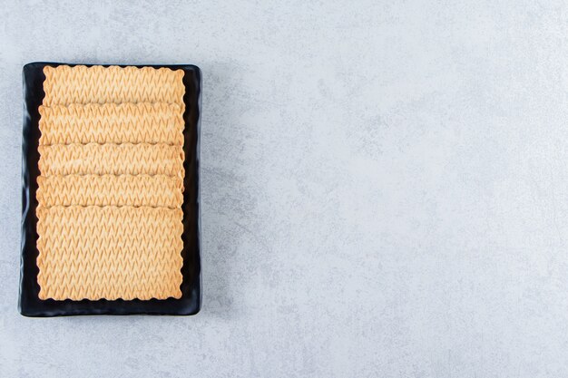 Black plate of tasty biscuits placed on stone.