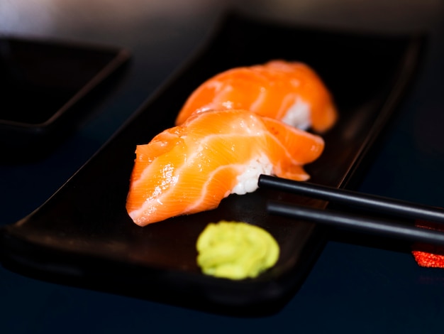 Free photo black plate with salmon sushi and wasabi