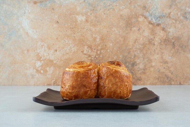 A black plate with sweet delicious pastry on white table.