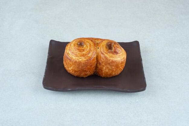 A black plate with sweet delicious pastry on white table.