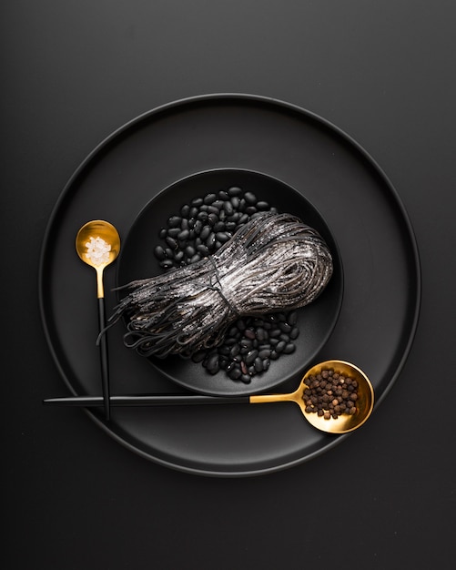 Black plates with pasta and beans on a dark background