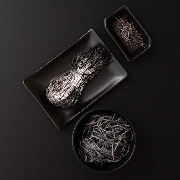 Free photo black plates with pasta on a dark background