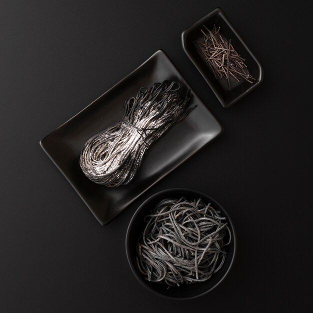 Black plates with pasta on a dark background