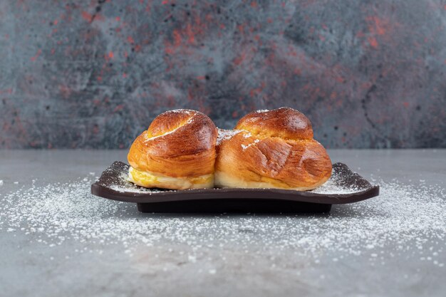 Black platter with sweet buns on marble