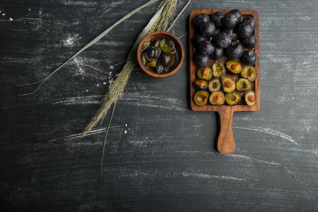 Black plums with its sauce on a wooden platter, top view