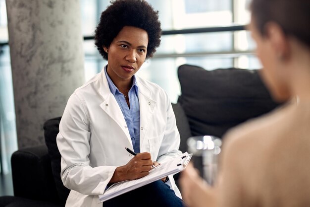 Black psychotherapist taking notes during a session with her patient