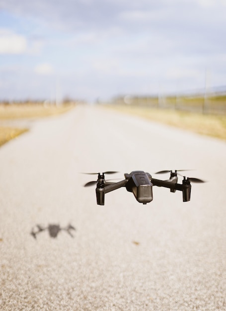 Black quadcopter drone over a cloudy sky