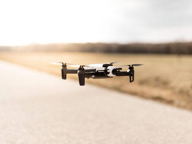 Black quadcopter drone over a cloudy sky