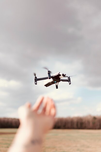 Black quadcopter drone over a cloudy sky