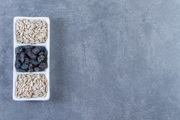 Black raisins and peeled seed in a dish , on the marble background.