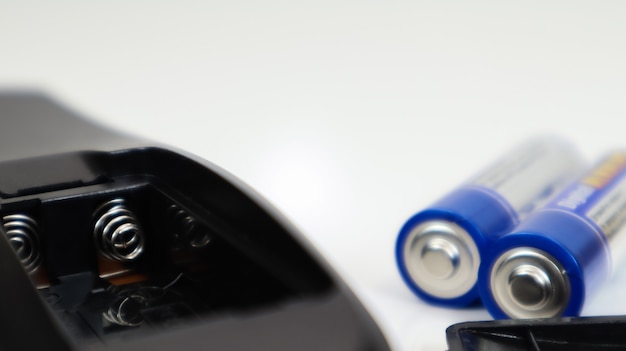 Черный пульт дистанционного управления с синими батарейками ааа на белом фоне. замена акб, запчасти. батарея пустой отсек пульта дистанционного управления крупным планом.