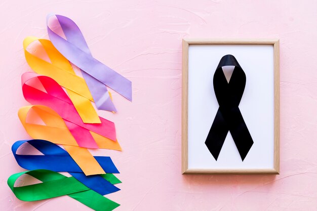 Black ribbon on white wooden frame near the row of colorful awareness ribbon