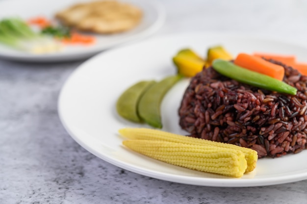 Black rice on a plate with pumpkin, peas, carrots, baby corn