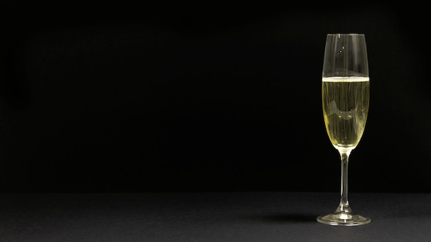 Бесплатное фото Черная сцена с бокалом шампанского.