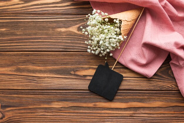 黒のスピーチの小道具と木製の織り目加工の背景にピンクの織物のアイスクリームコーンの中の石膏