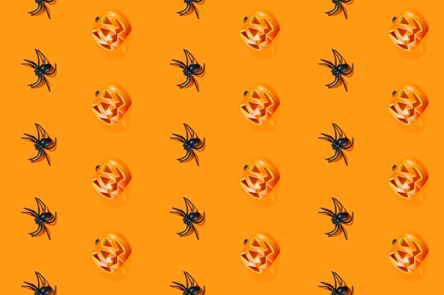 Black spiders and Halloween pumpkins laid in lines