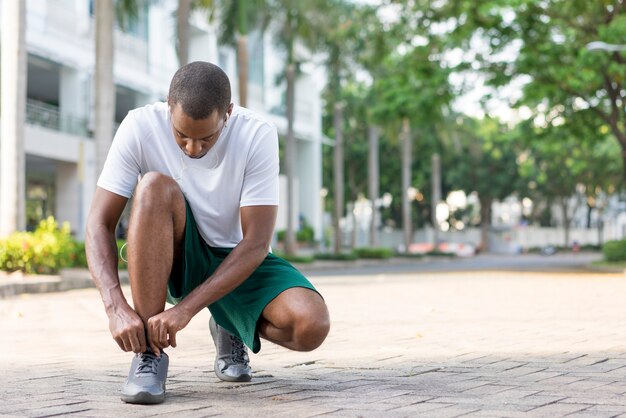 Black sportsman getting ready for morning run down walkway. 