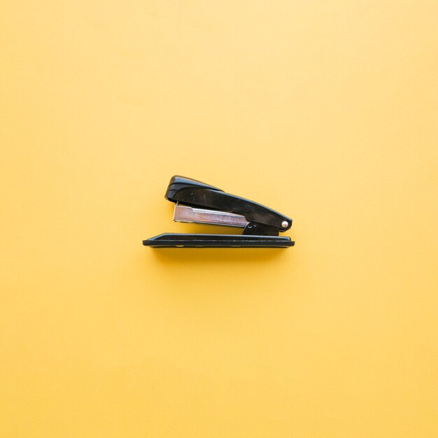 Black stapler on orange background 