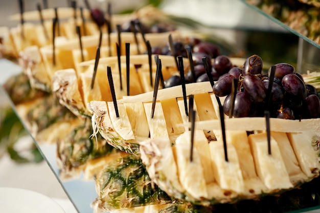 Black stick put in pieces of ananas on long glass plate 