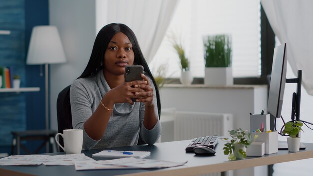 Black student holding phone in hands chatting with people browsing communication information