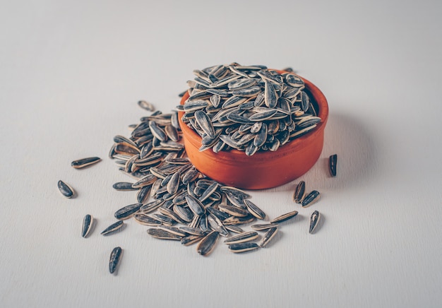 Free photo black sunflower seeds in a bowl on a white background. high angle view.