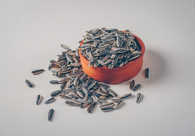 Black sunflower seeds in a bowl on a white background. high angle view.