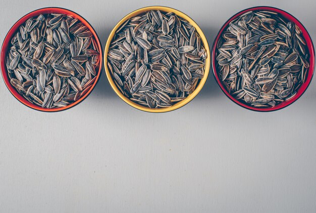 Black sunflower seeds in a bowls on a white background. top view. space for text