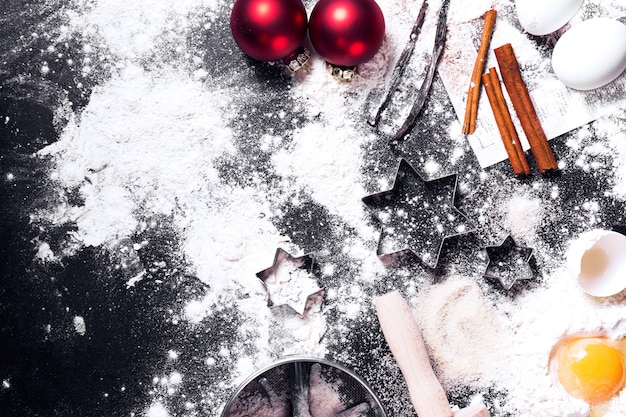 クリスマスの飾りと小麦粉と卵の完全な黒テーブル