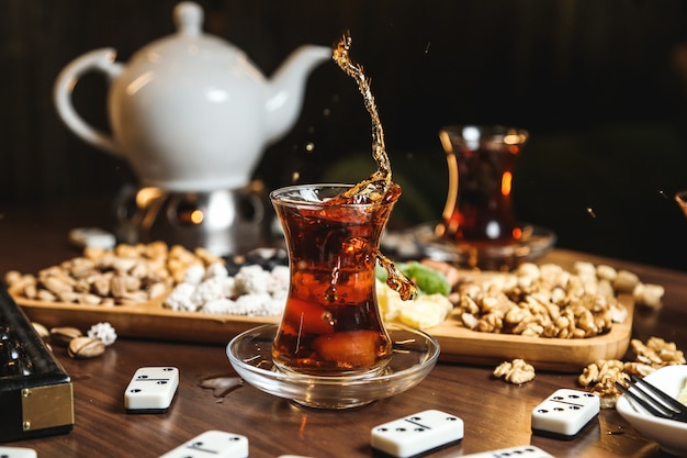 Черный чай в стакане армуду с различными сладостями на столе крупным планом