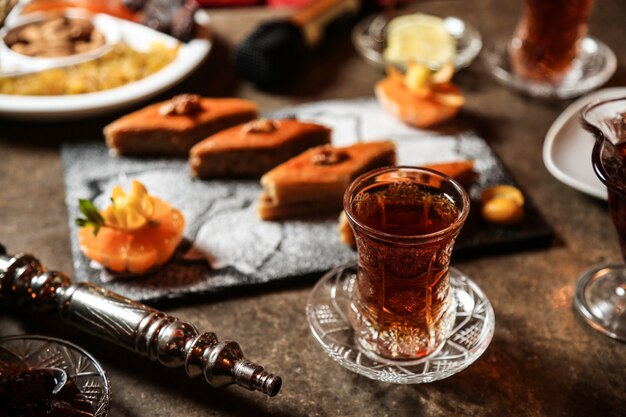 Black tea in armudu glass with various sweets on the table