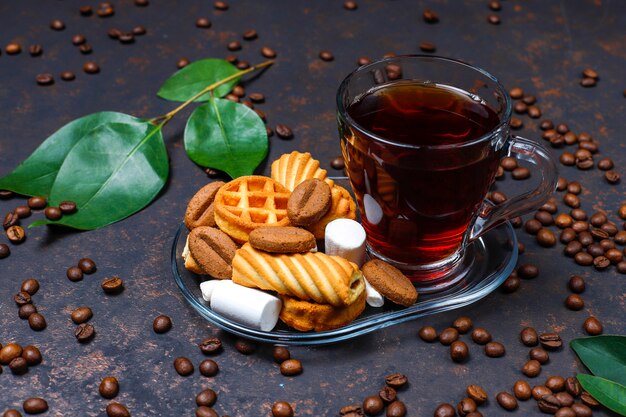 Black tea in glass cup with sweets on dark