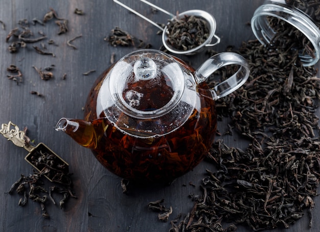 Free photo black tea with dry tea in a teapot on wooden surface