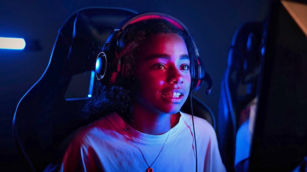 Free photo black teen smiling girl in headset playing video games in video game club