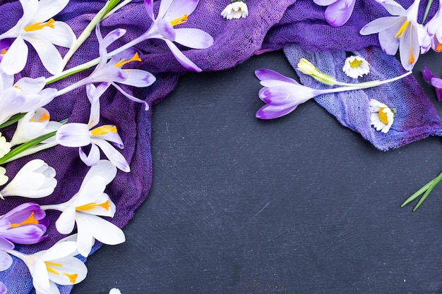 Black textured background with purple dyed cloth and spring flowers