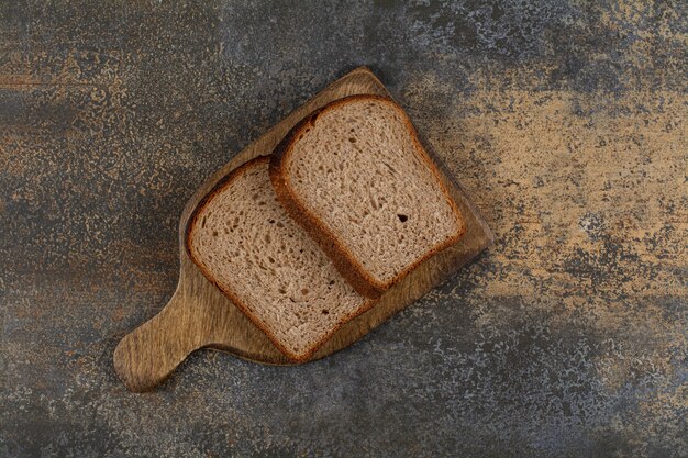 Черный тостовый хлеб на деревянной доске.