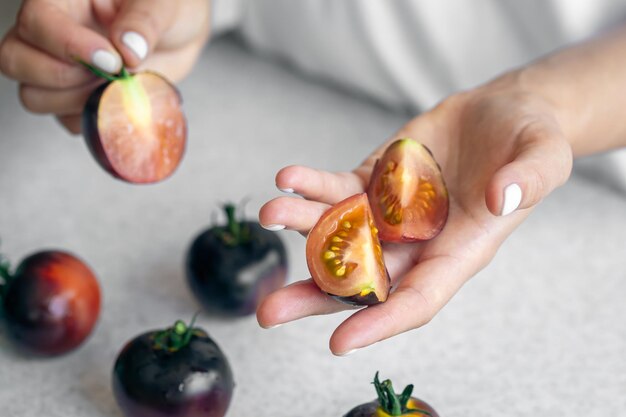 Черные помидоры в женских руках крупным планом готовят на кухне