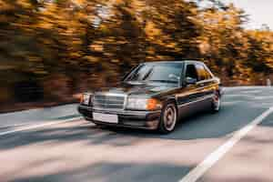 Free photo a black vintage car driving on the road longing accross the forest.