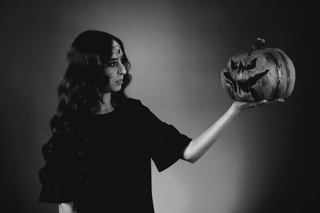 Black and white photo of girl looking at pumpkin