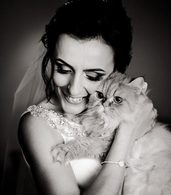 Черно-белое изображение счастливой невесты, холдинг пушистый кот за ее лицо