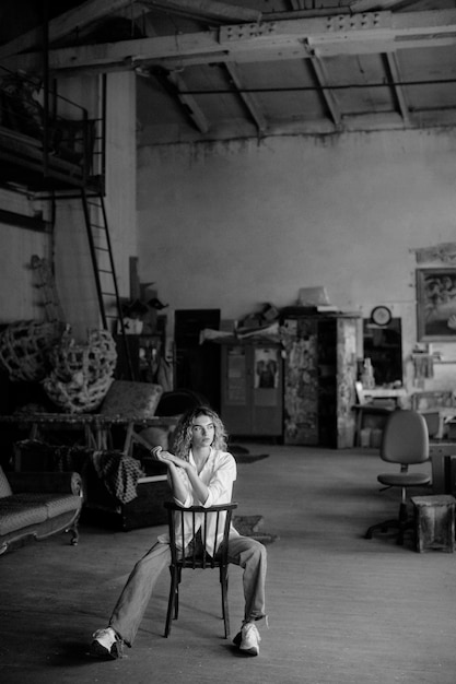 Free photo black and white portrait of beautiful woman posing indoors on a chair