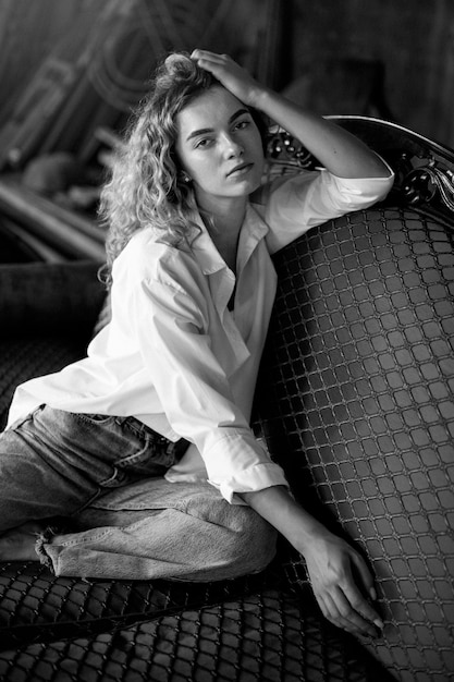 Black and white portrait of beautiful woman posing indoors on a couch