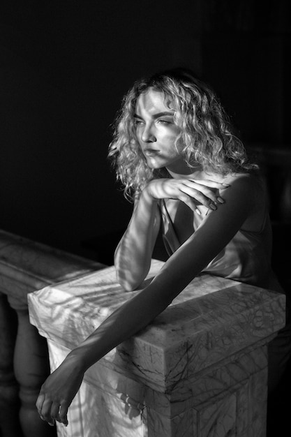 Black and white portrait of beautiful woman posing indoors in a dress