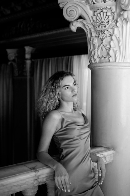 Black and white portrait of beautiful woman posing indoors in a dress