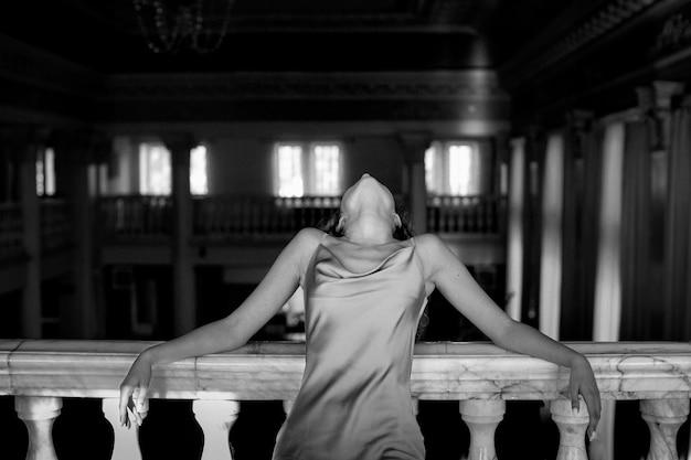 Черно-белый портрет красивой женщины, позирующей в помещении в платье
