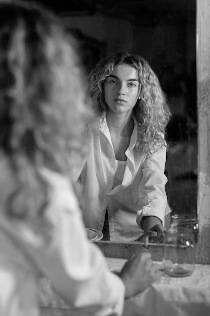 Черно-белый портрет красивой женщины, позирующей в помещении перед зеркалом