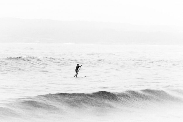 Черно-белый снимок человека посреди моря