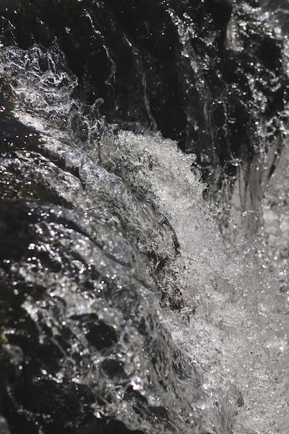 Black and white vertical shot of splashing water stream
